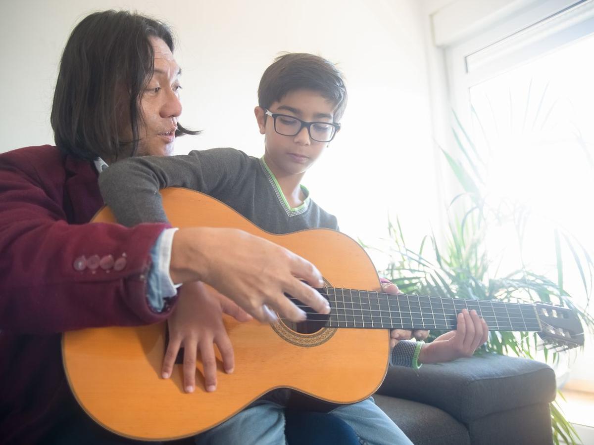Maestro enseñando guitarra a un niño